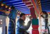12月28日，西藏拉萨堆龙德庆区，古俗民族传统手工艺发展专业合作社员工在房屋上绘制藏式装饰。中新社记者 贡嘎来松　摄